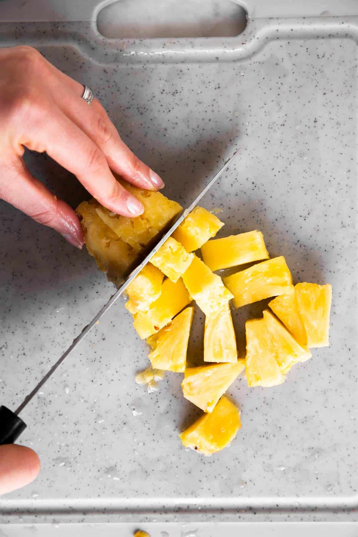 female hands cutting pineapple chunks