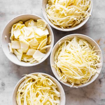 four white bowls with differently sliced cabbage inside