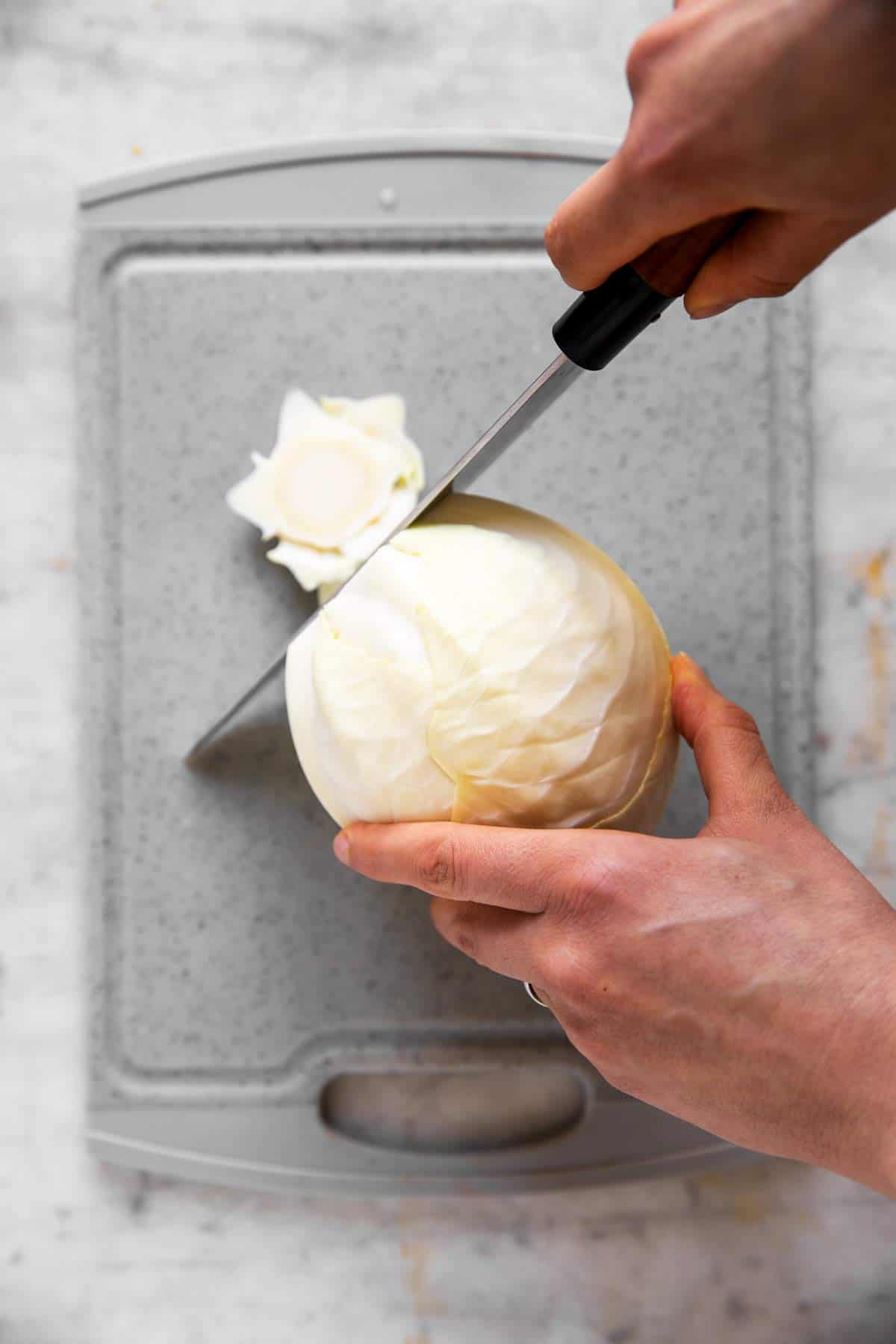 female hands trimming bottom part of a white cabbage