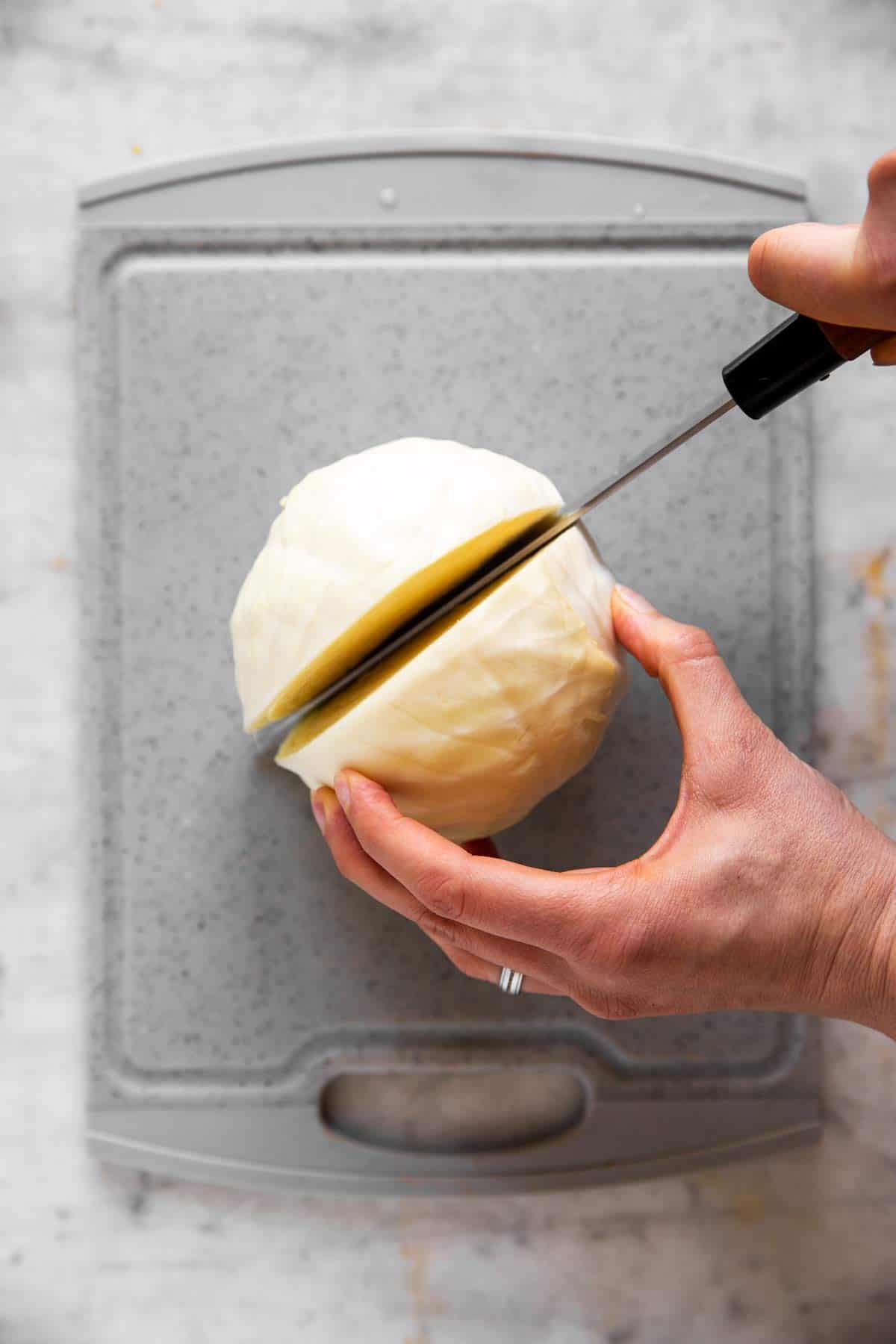 female hands cutting white cabbage in half