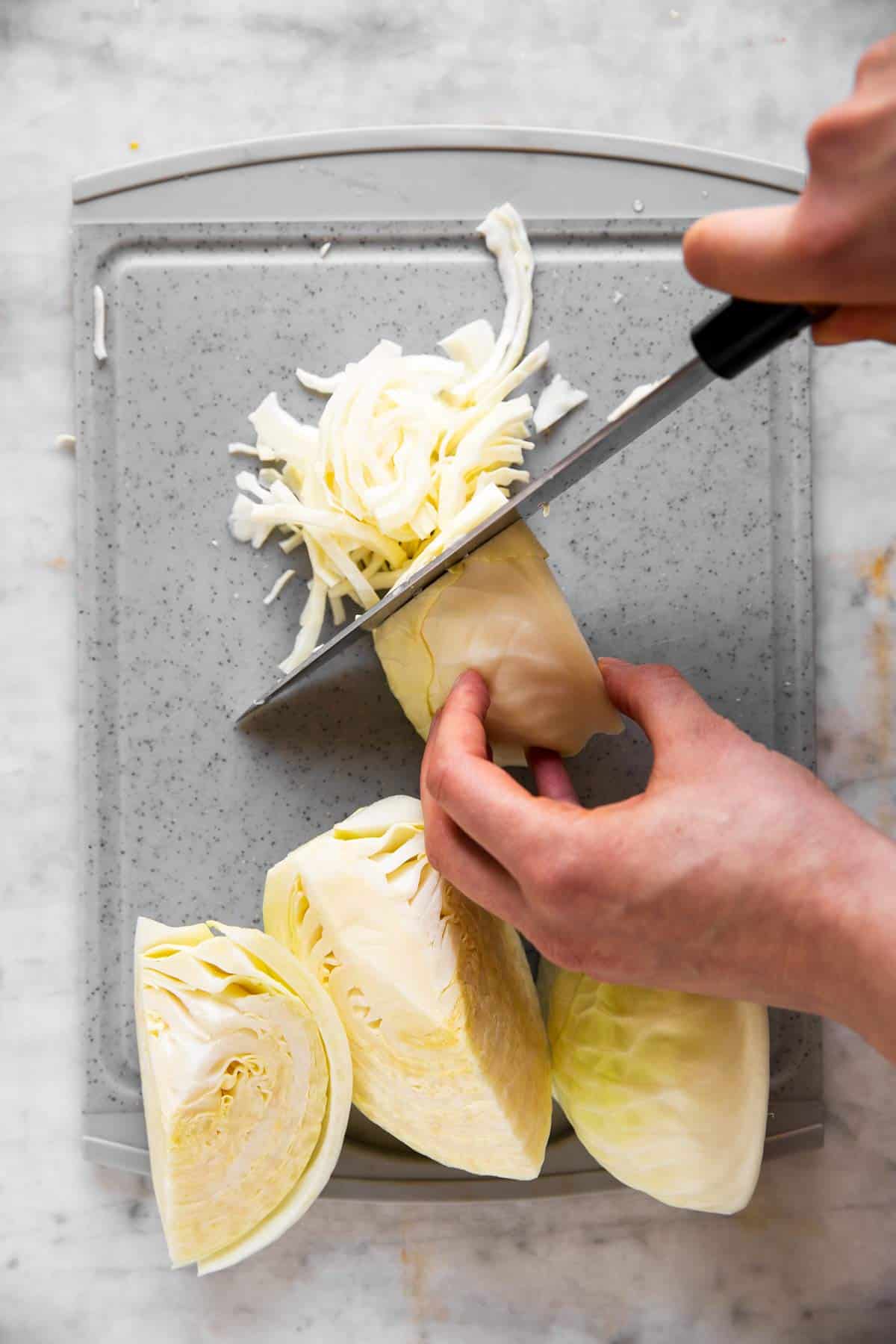 female hands shredding white cabbage into short shreds