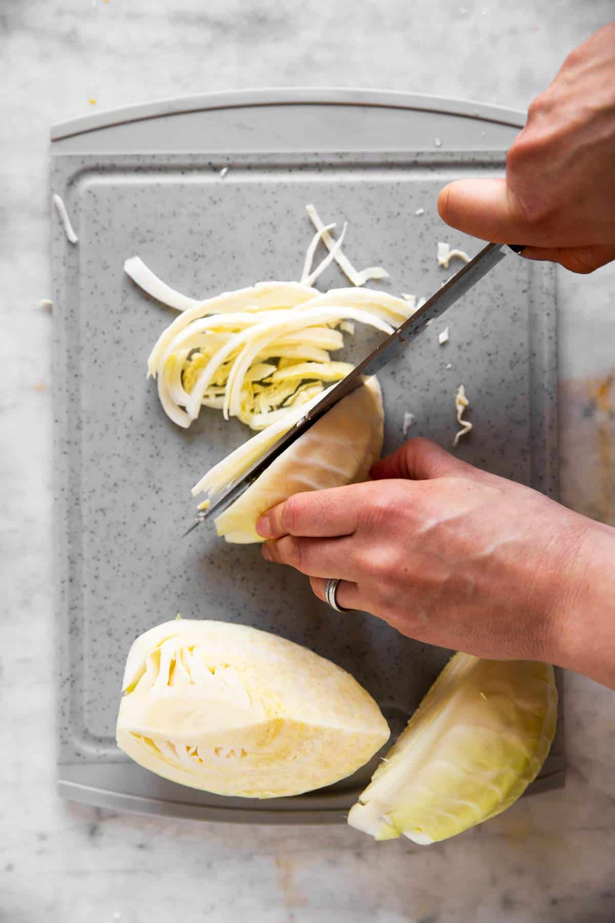 female hands shredding white cabbage into long shreds