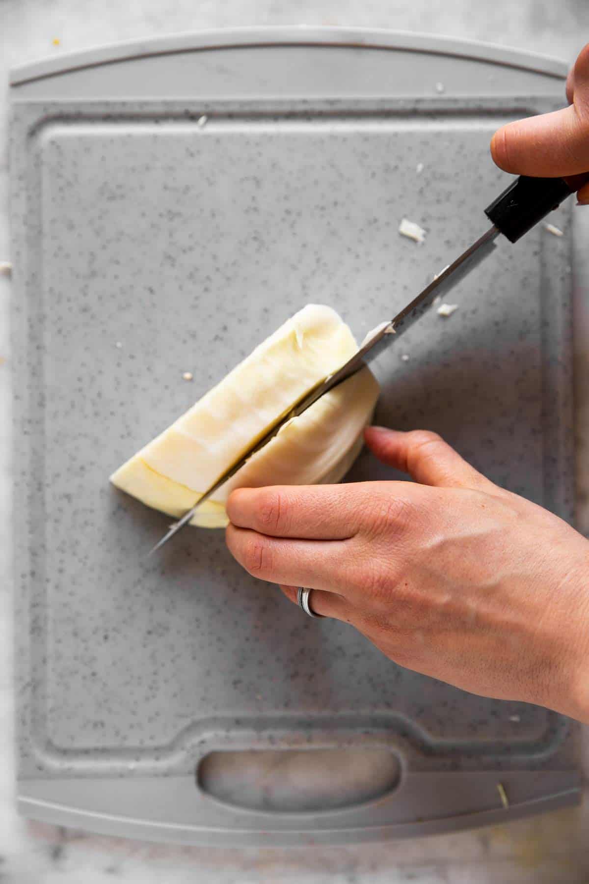 female hands cutting white cabbage into thick strips