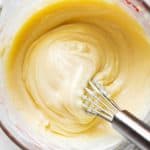 overhead view of homemade mayonnaise in glass measuring jug with metal whisk stuck in