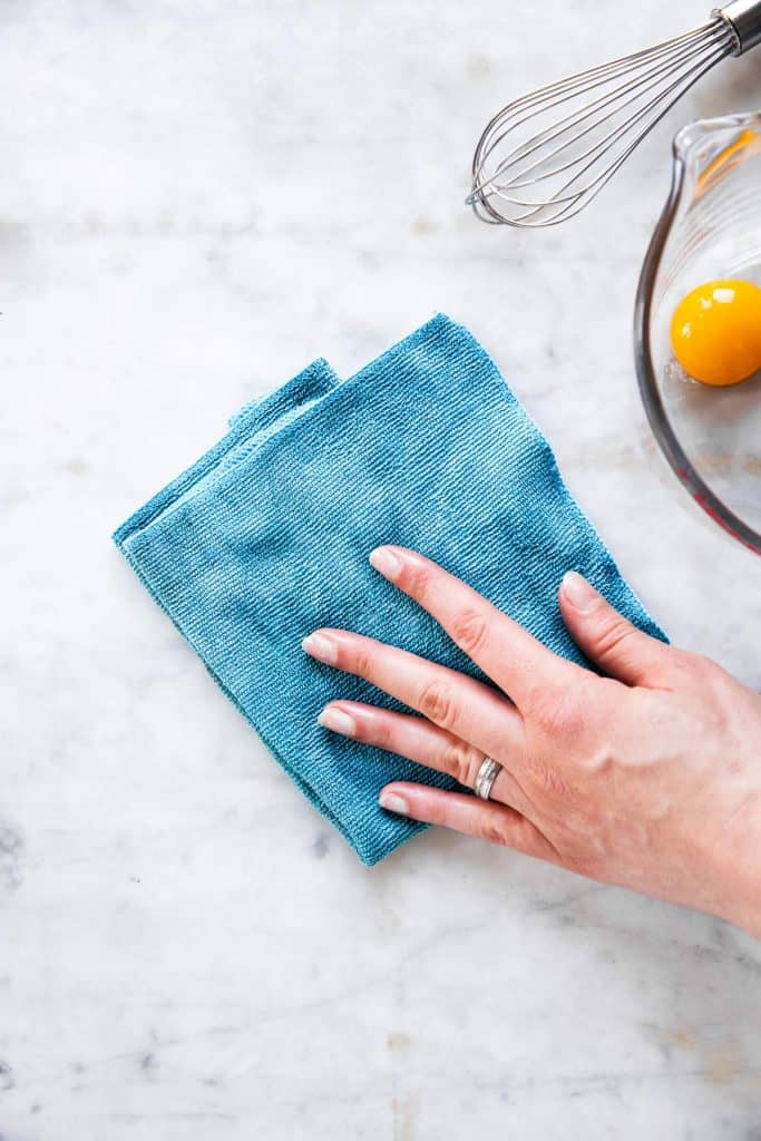 female hand placing down blue cloth on marble countertop