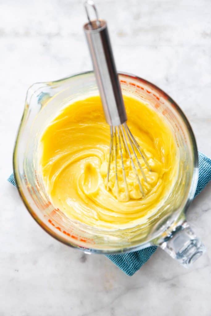 half-made mayonnaise in glass measuring jug with metal whisk stuck inside