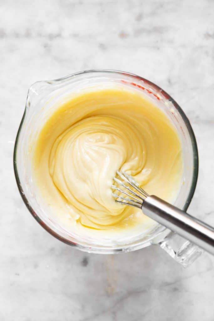 homemade mayonnaise in glass measuring jug after adding seasoning