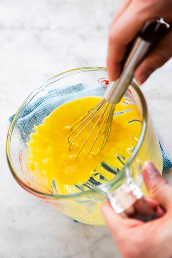egg yolks in glass measuring jug after having been whisked together with mustard