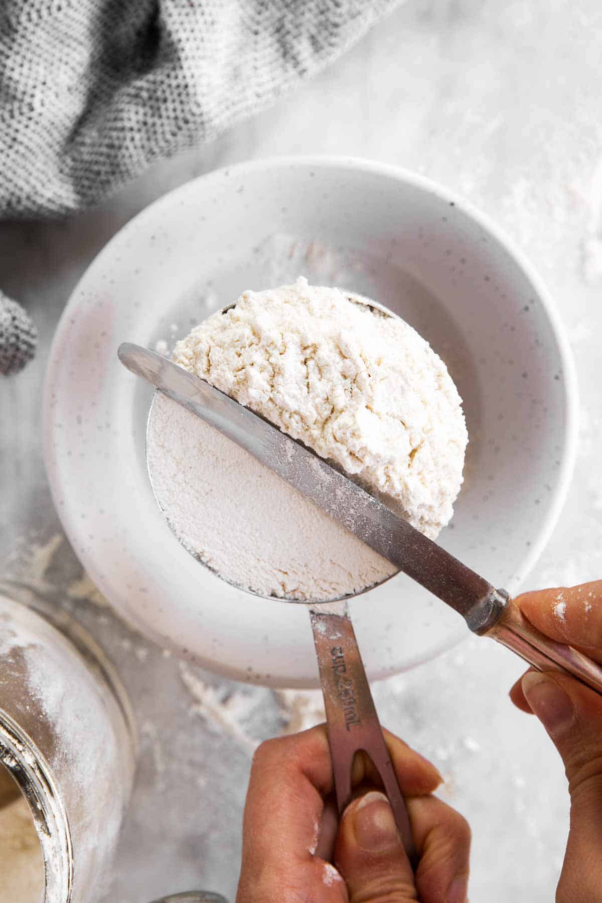 female hand levelling cup of flour with the back of a  knife