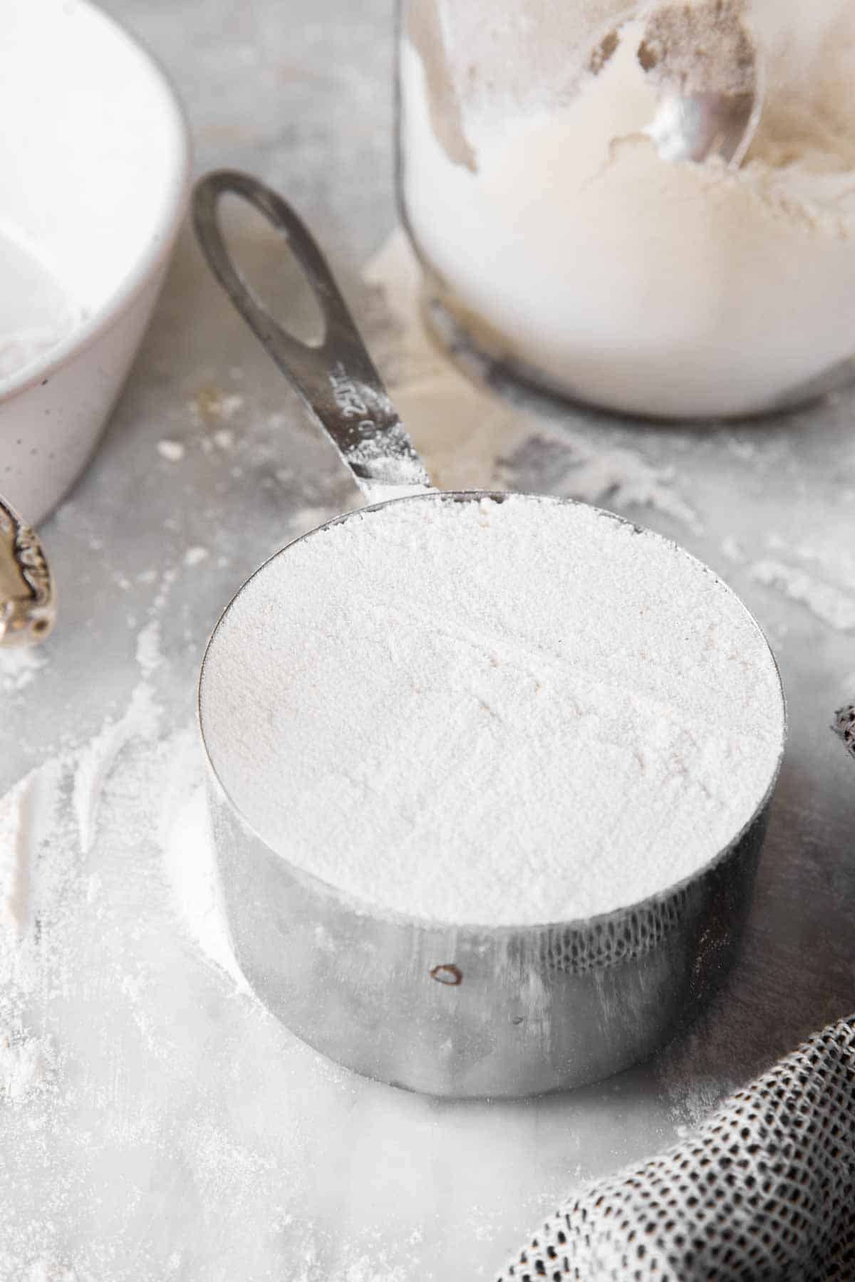 measuring cup filled with flour on marble surface