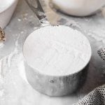 measuring cup filled with flour on marble surface