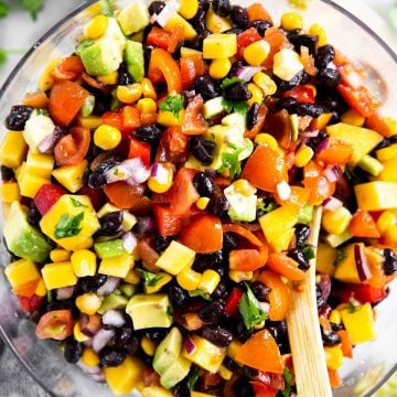 overhead photo of mango black bean salsa in glass bowl with wooden spoon