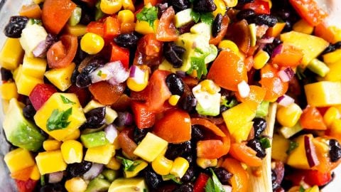 overhead photo of mango black bean salsa in glass bowl with wooden spoon