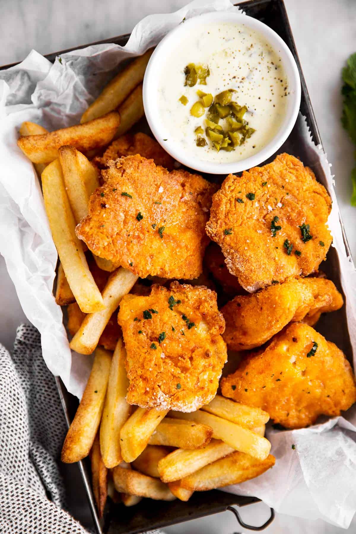 black tray with oven fried fish, French fries and tartar sauce