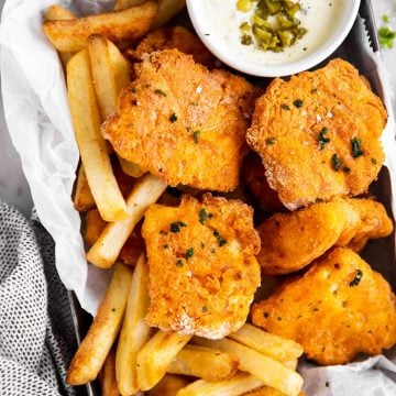 black tray with oven fried fish, French fries and tartar sauce