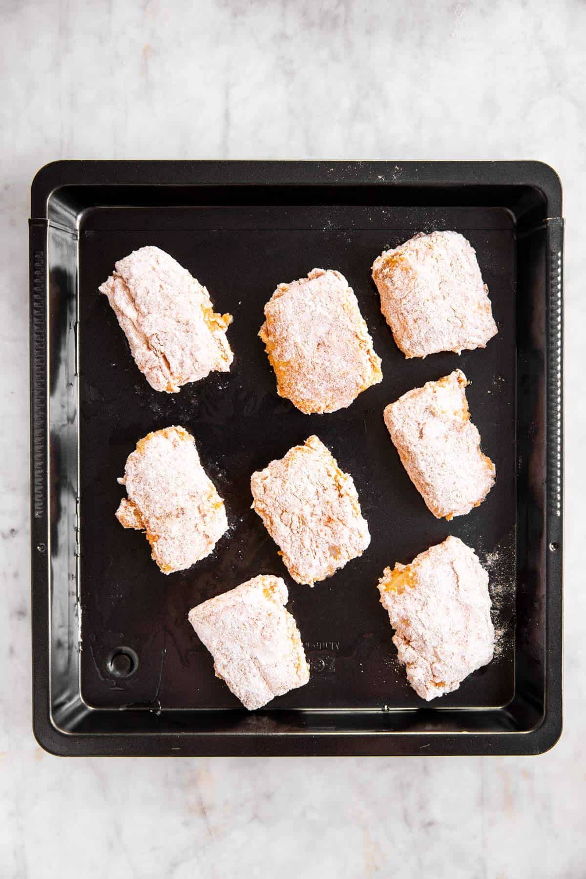 breaded fish pieces on black pan