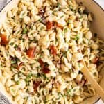 overhead view of pea and bacon pasta in white pot with wooden spoon