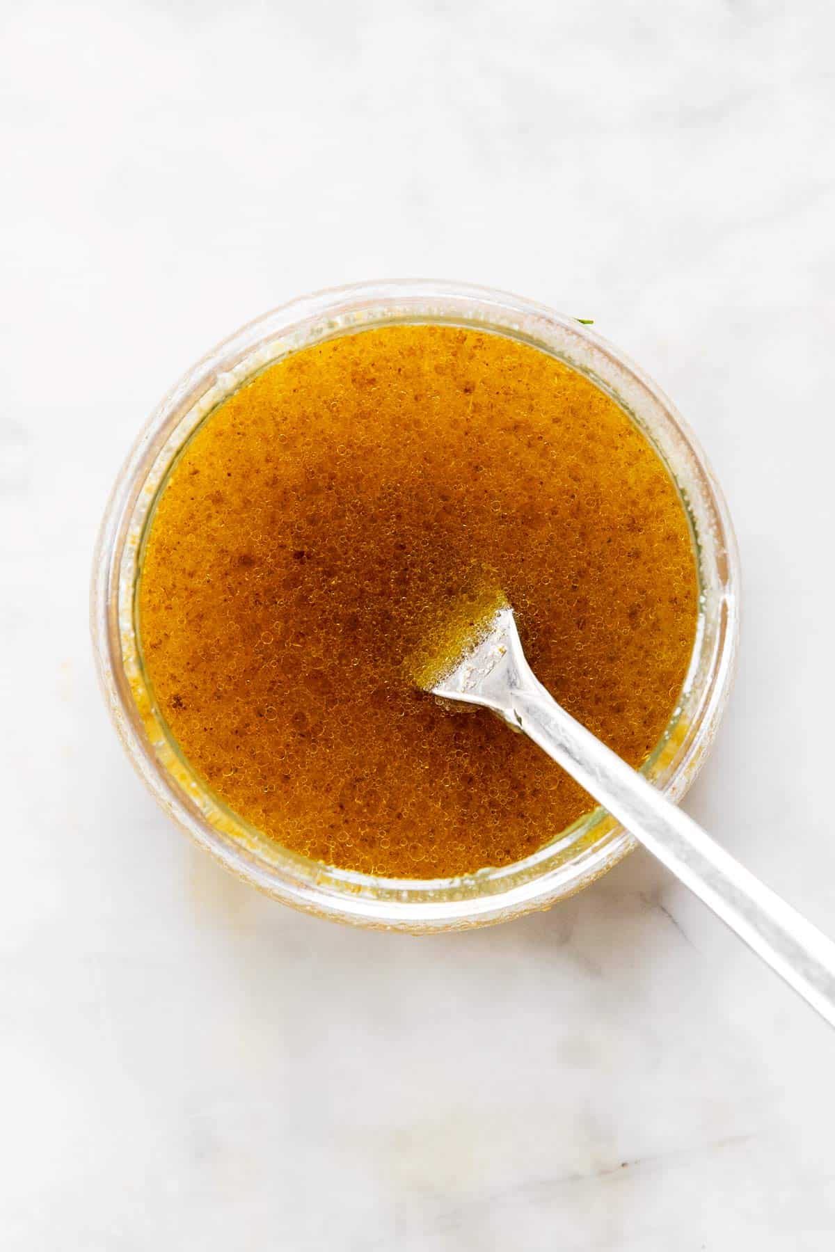 honey lime dressing in a small glass jar with a fork inside