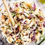 pineapple coleslaw in glass bowl with wooden salad tongs