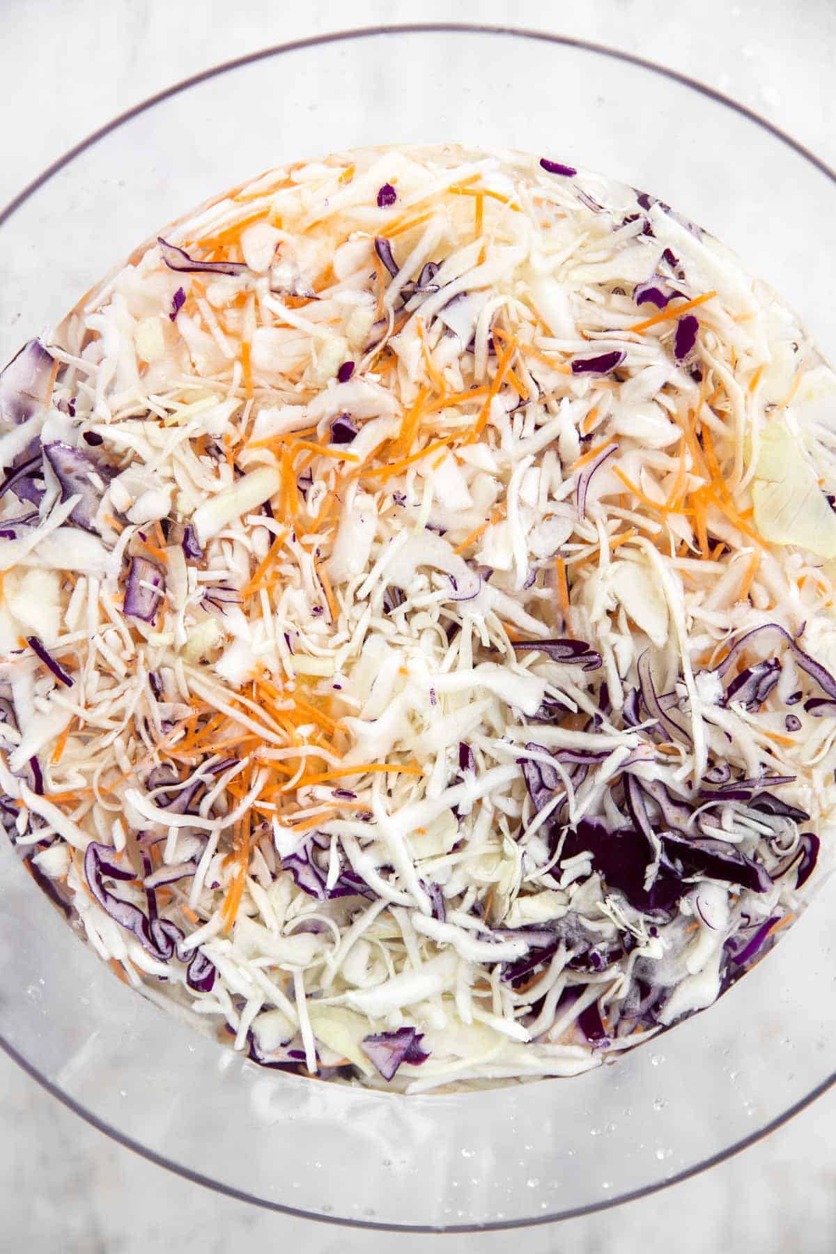 coleslaw mix soaking in water in glass bowl