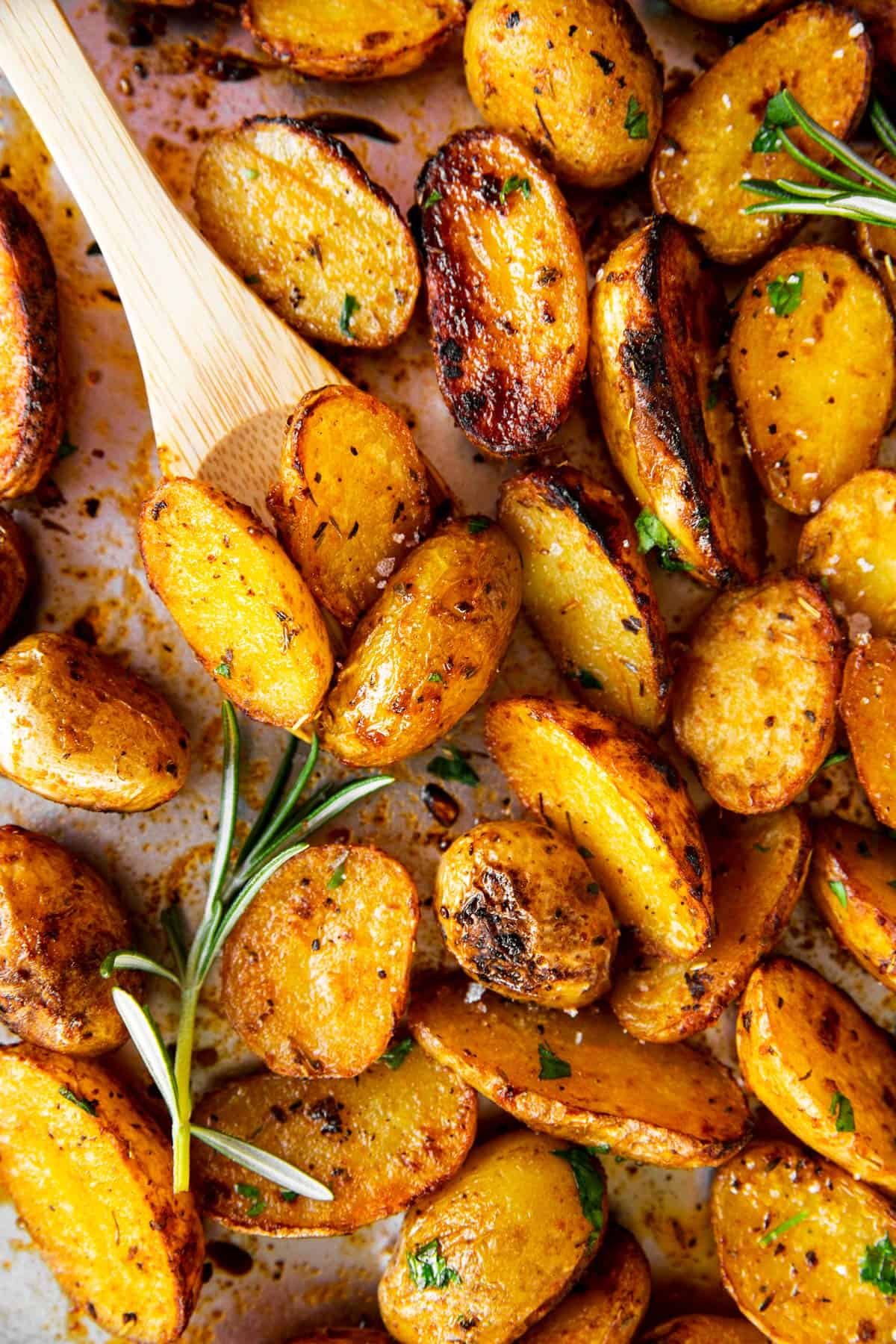 overhead close up view of roasted baby potatoes on pan with wooden spoon