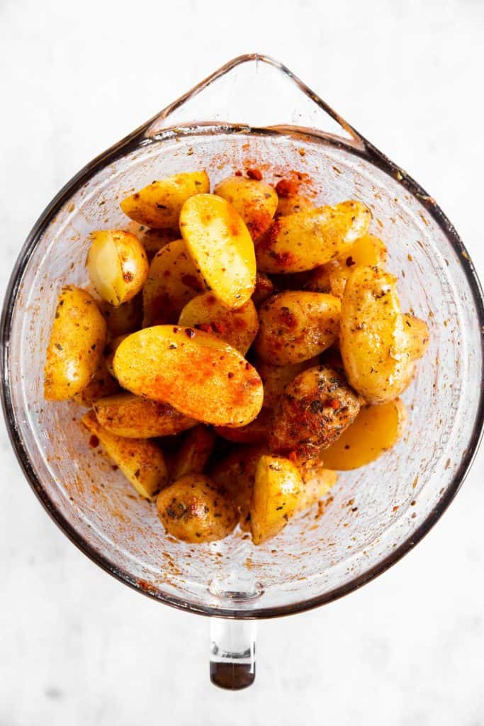 raw baby potatoes in glass bowl with seasoning