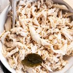 overhead view of white bowl filled with shredded chicken