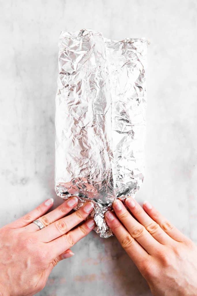 female hands folding foil packet edge into a triangle 