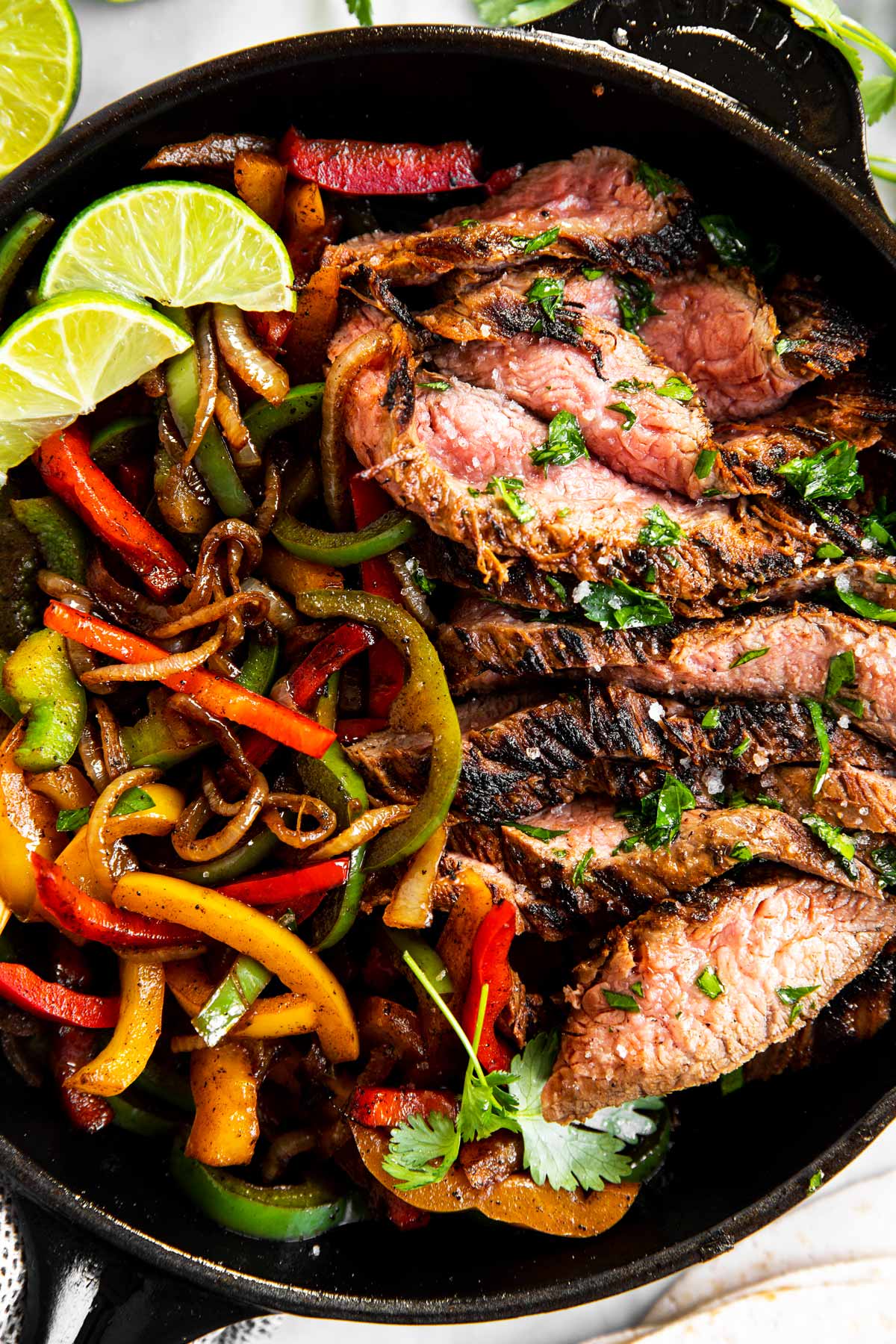 close up photo of black cast iron skillet with steak fajita filling