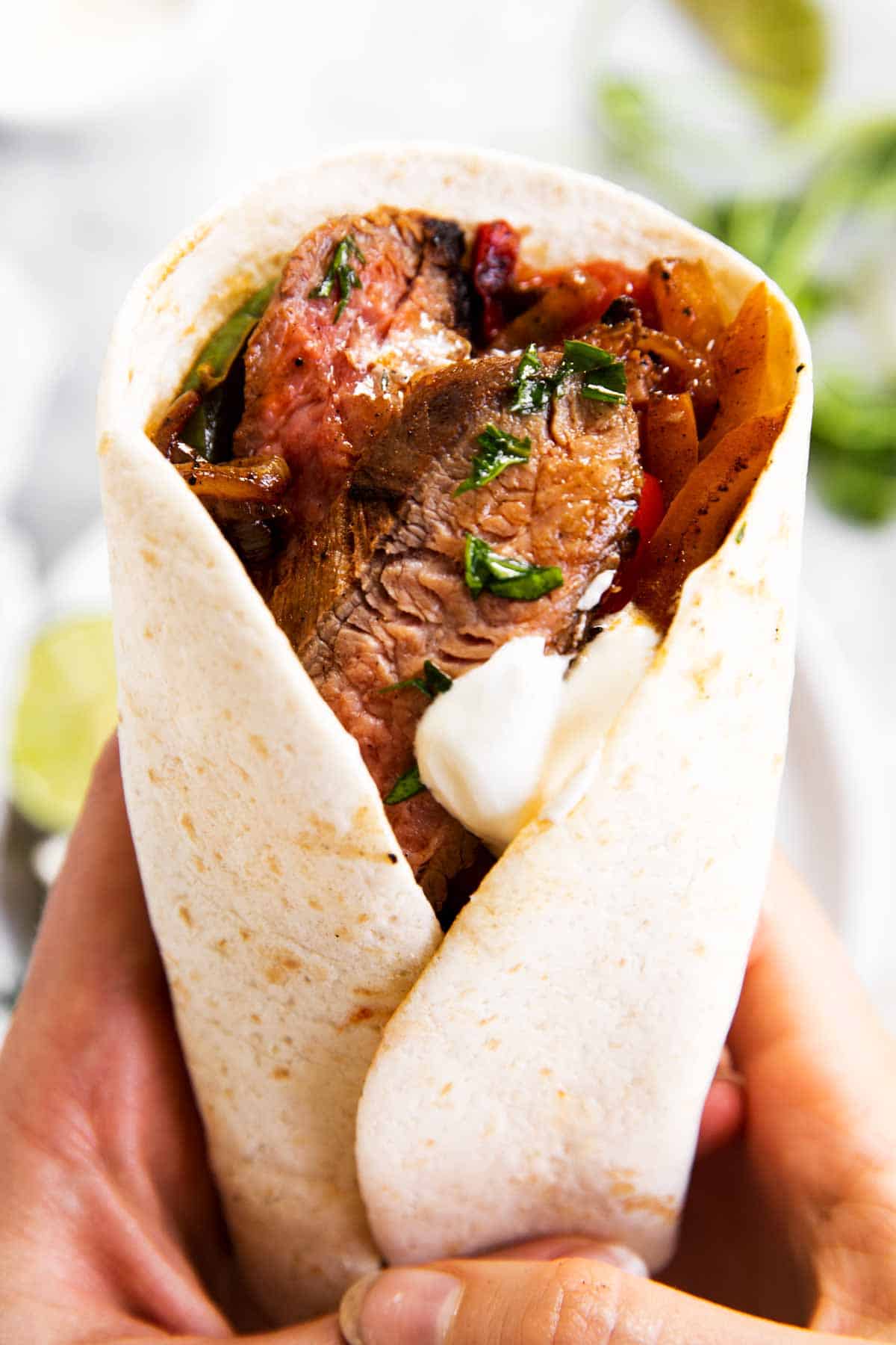 female hands holding a steak fajita