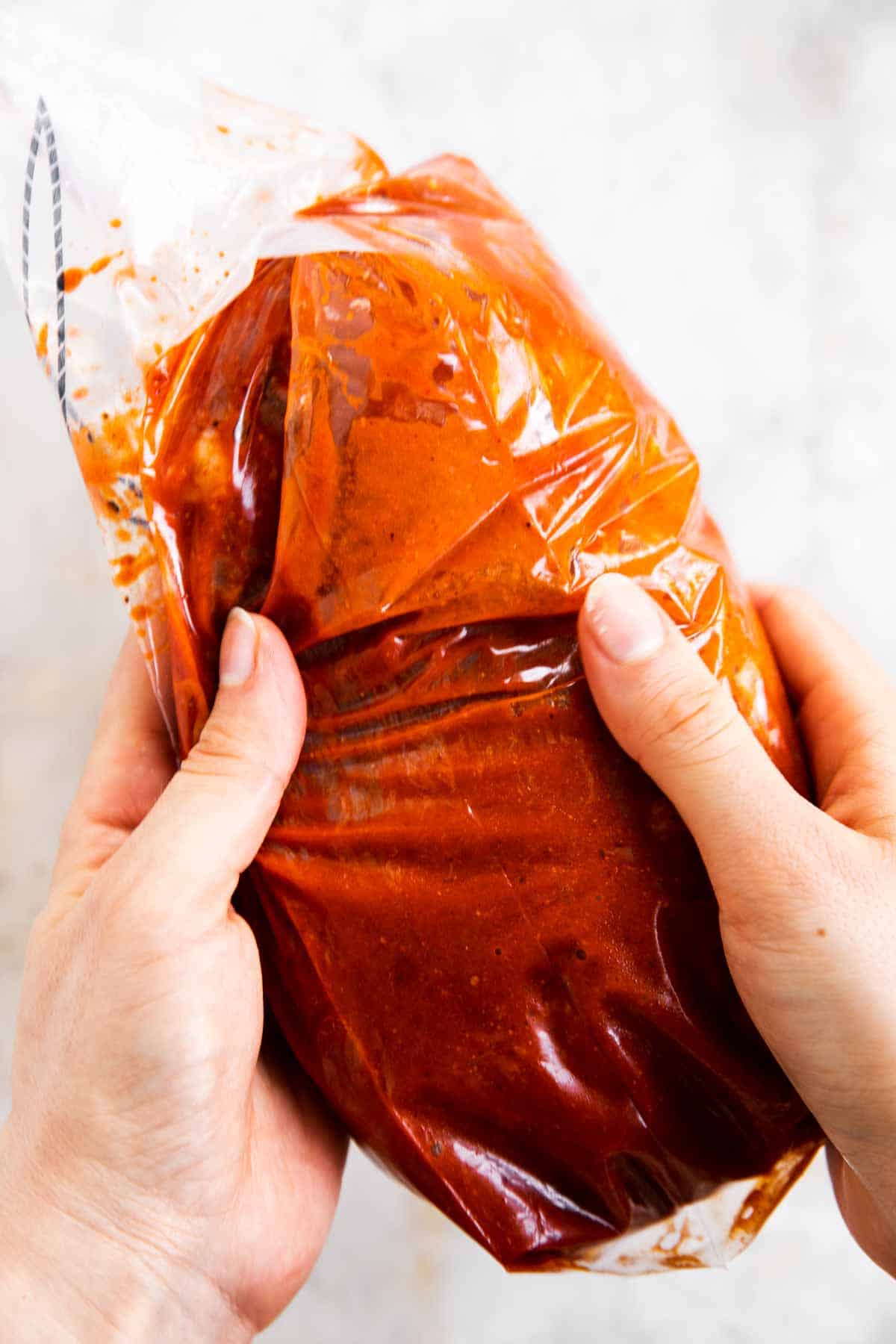 female hands holding bag with steak in fajita marinade