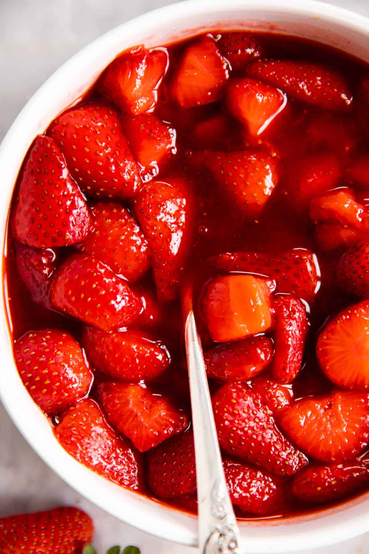 overhead view of strawberry sauce in white bowl with a spoon