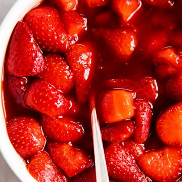 overhead view of strawberry sauce in white bowl with a spoon