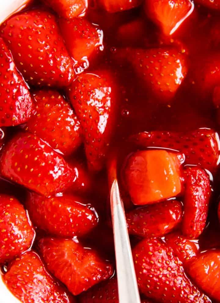 overhead view of strawberry sauce in white bowl with a spoon