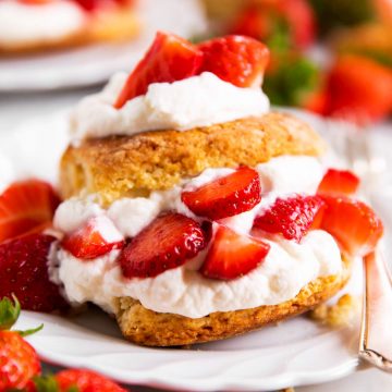 strawberry shortcake on white plate surrounded by fresh strawberries