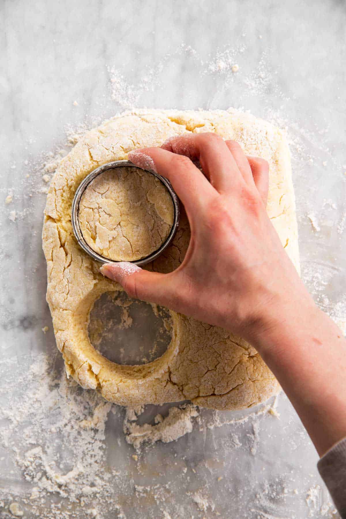 female hand using biscuit cutter on biscuit dough