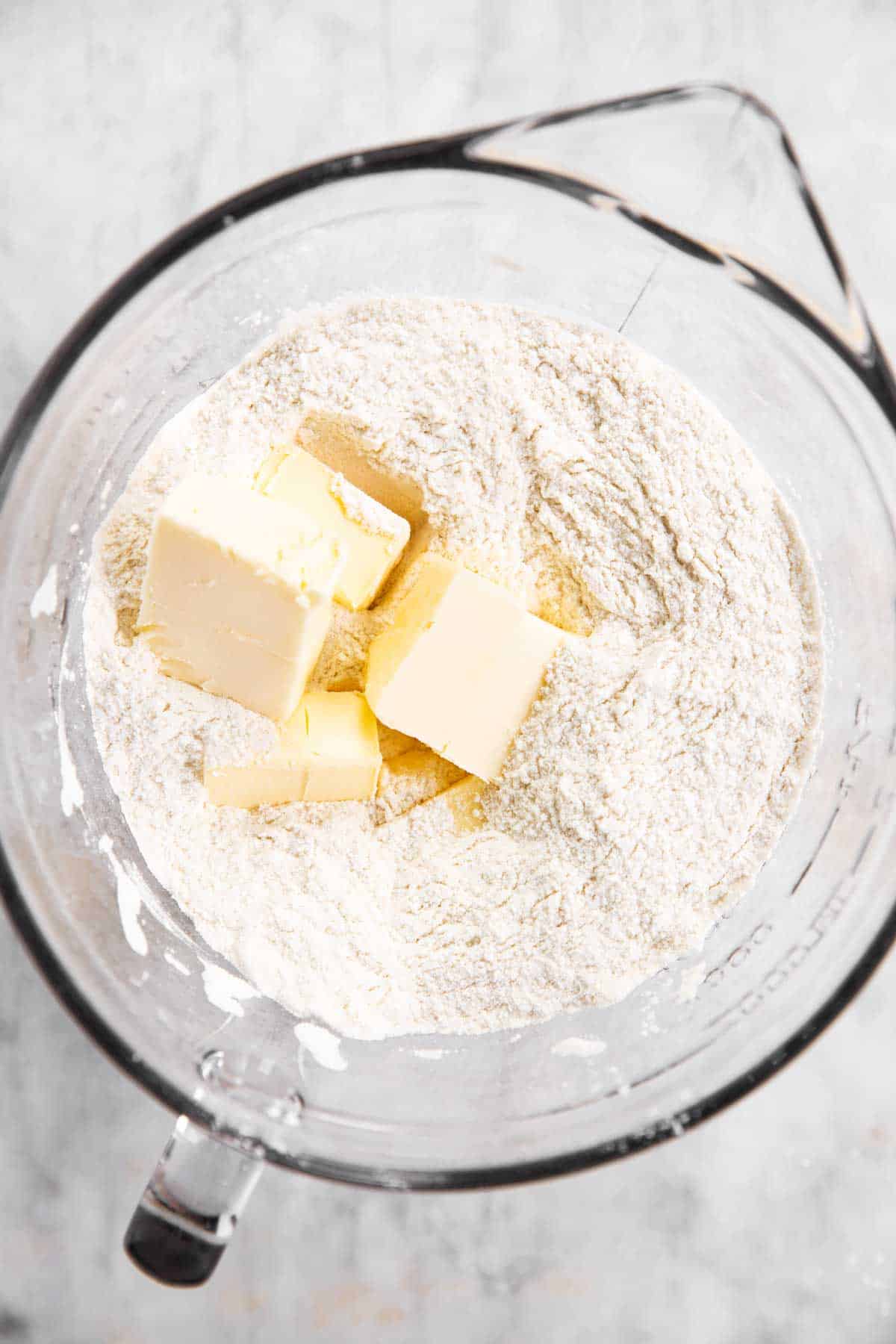 dry ingredients for shortcake biscuits in glass bowl with diced butter