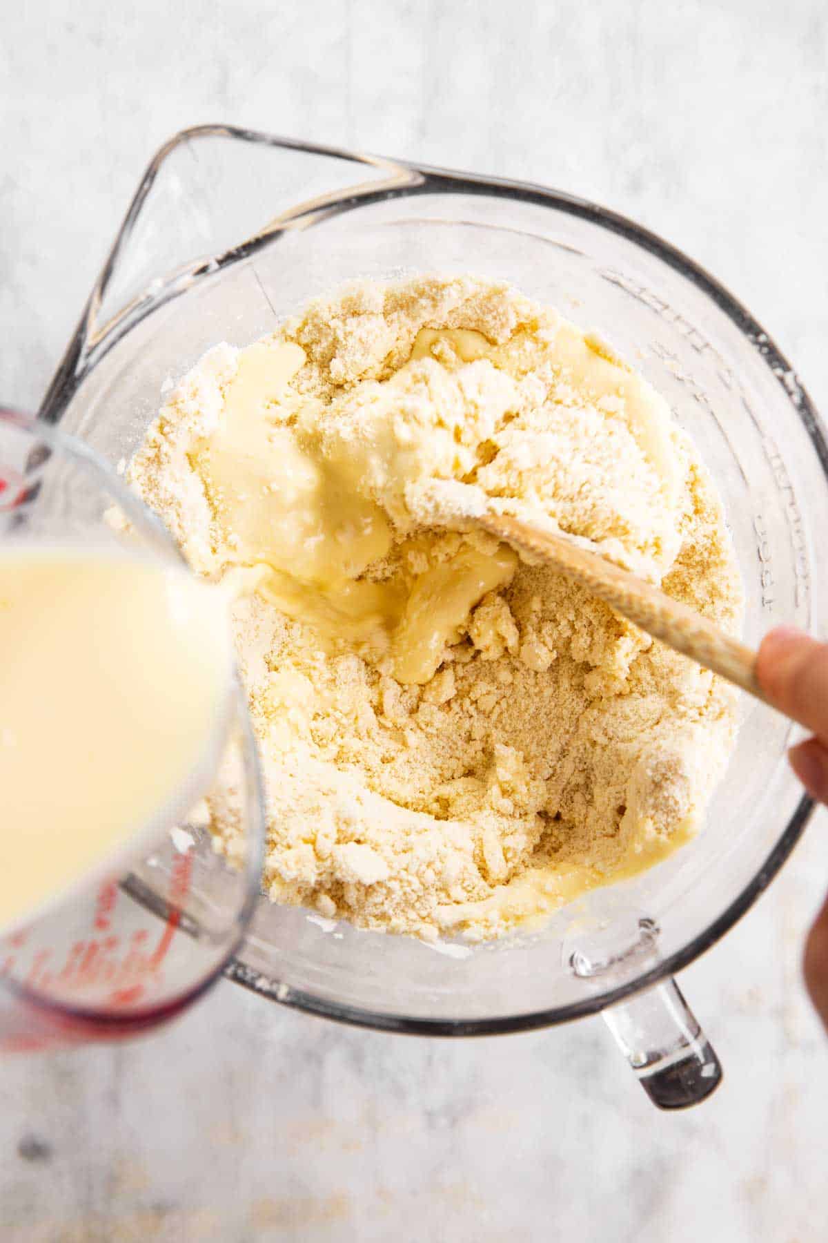 female hand pouring buttermilk mixture into dry ingredients for shortcake biscuits