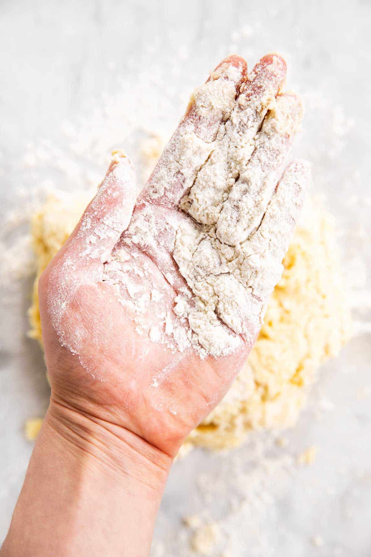 floured hand hovering over biscuit dough