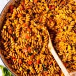 overhead view of taco pasta in white cast iron skillet with wooden spoon stuck inside