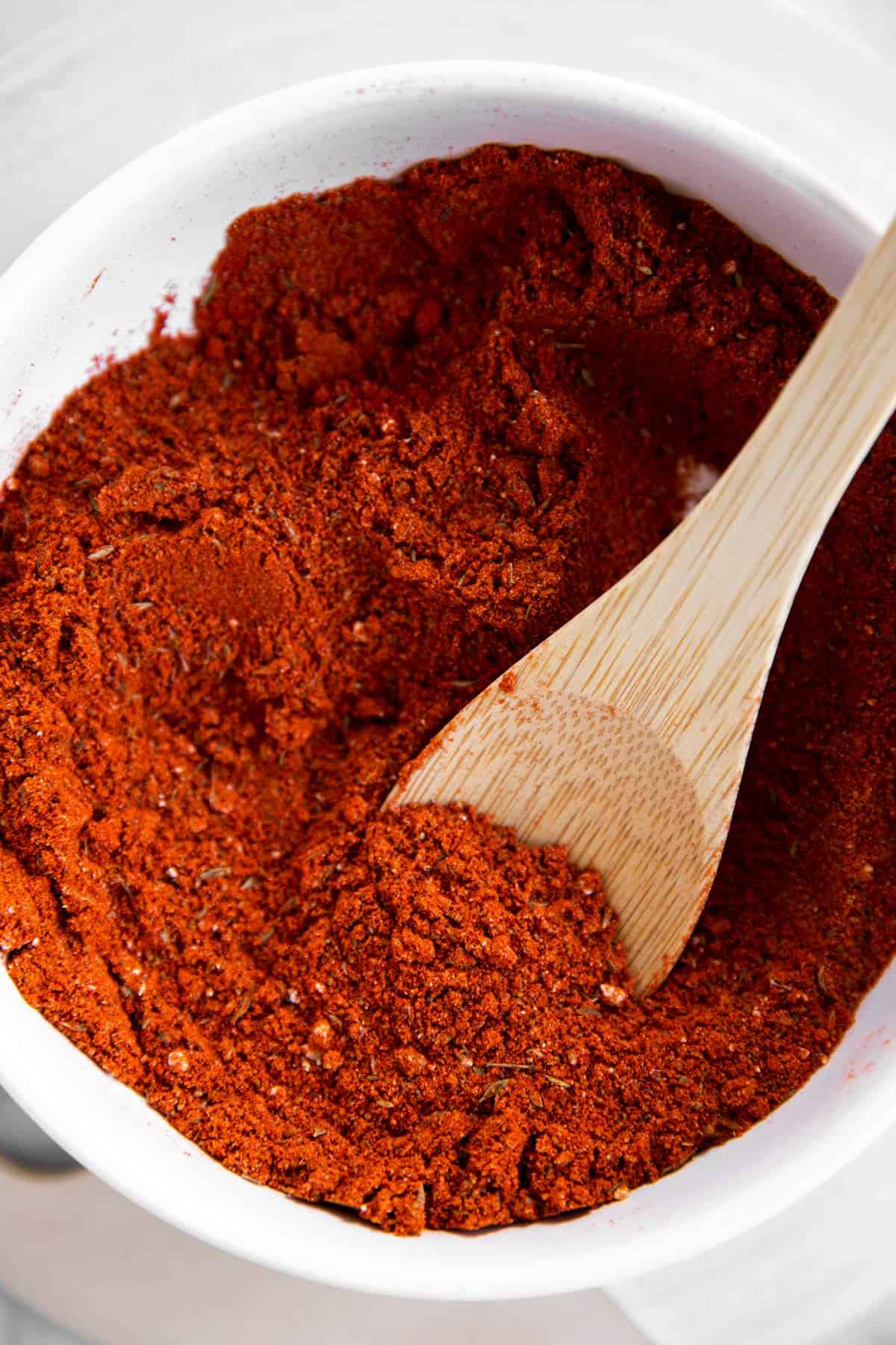 overhead view of wooden spoon in white bowl filled with homemade taco seasoning