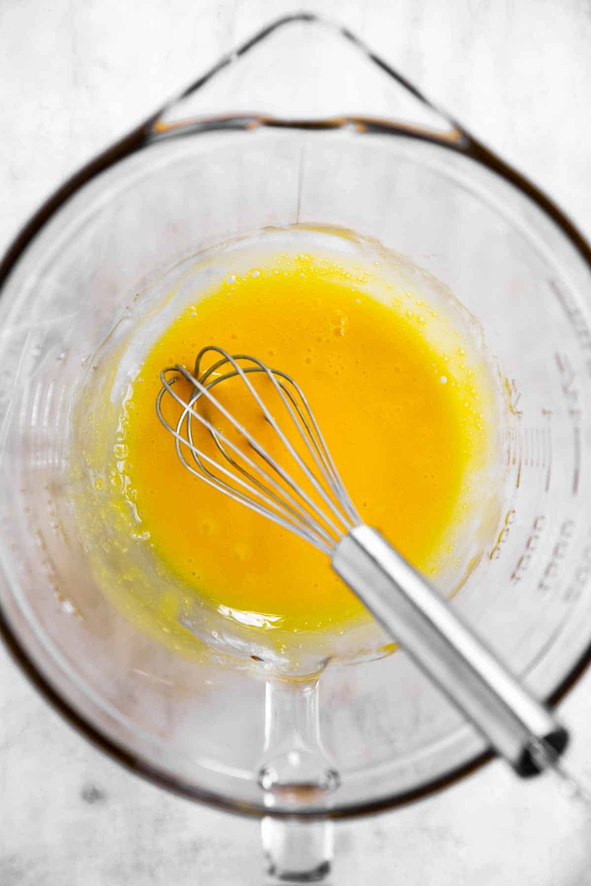 beaten egg yolks in glass bowl with whisk