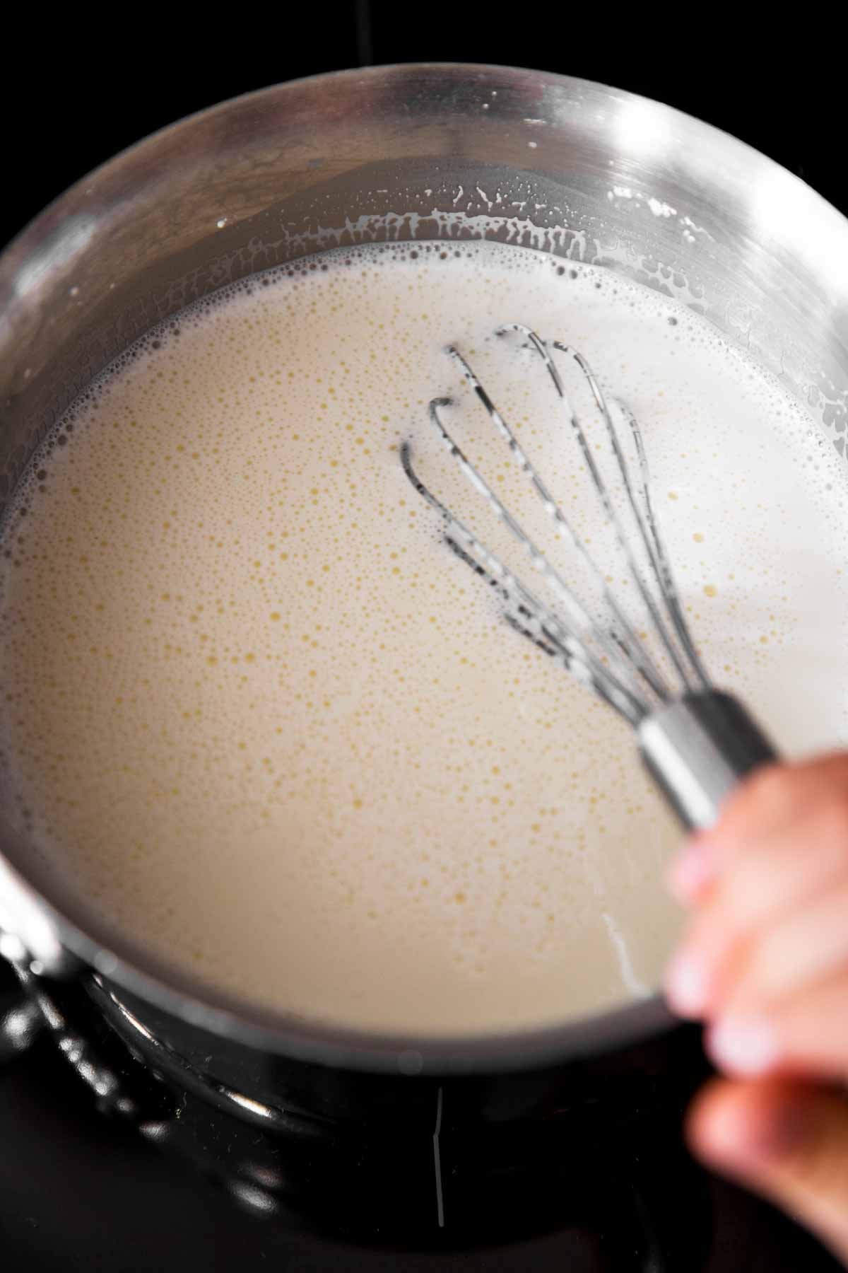 whisk in saucepan with milk on stove