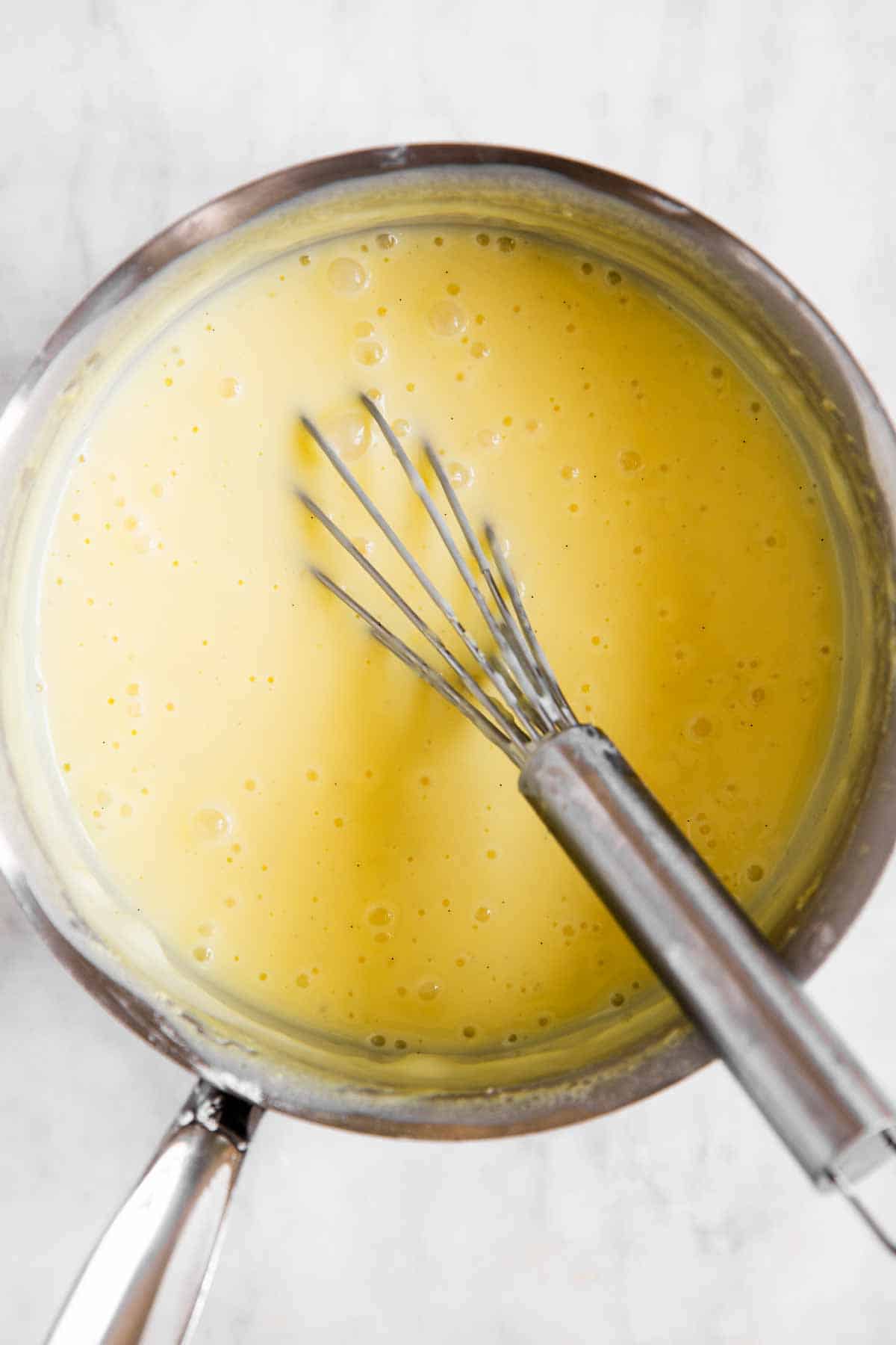cooked vanilla pudding in saucepan with whisk