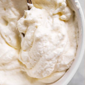 overhead view of whipped cream in white bowl with spoon