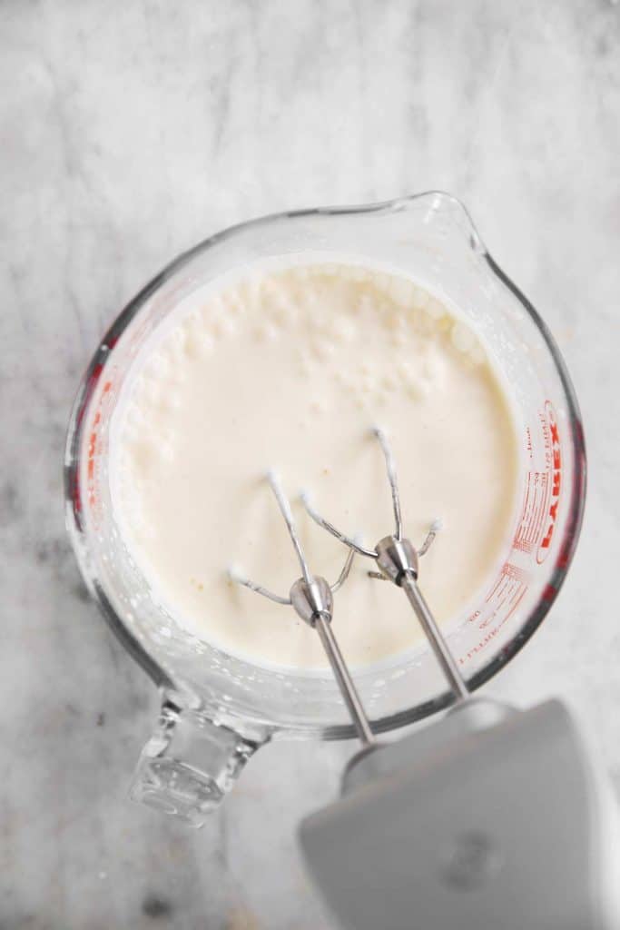 homemade whipped cream in glass measuring jug after one minute of whipping