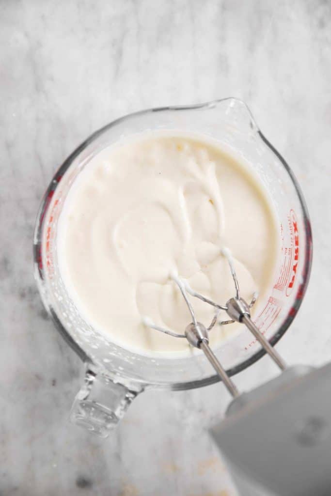 homemade whipped cream in glass measuring jug after two minutes of whipping