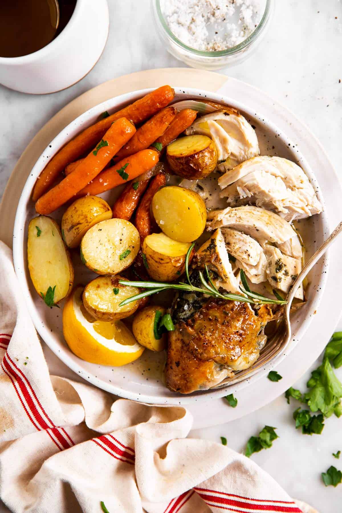 overhead view of carved chicken breast with potatoes and carrots on white plate