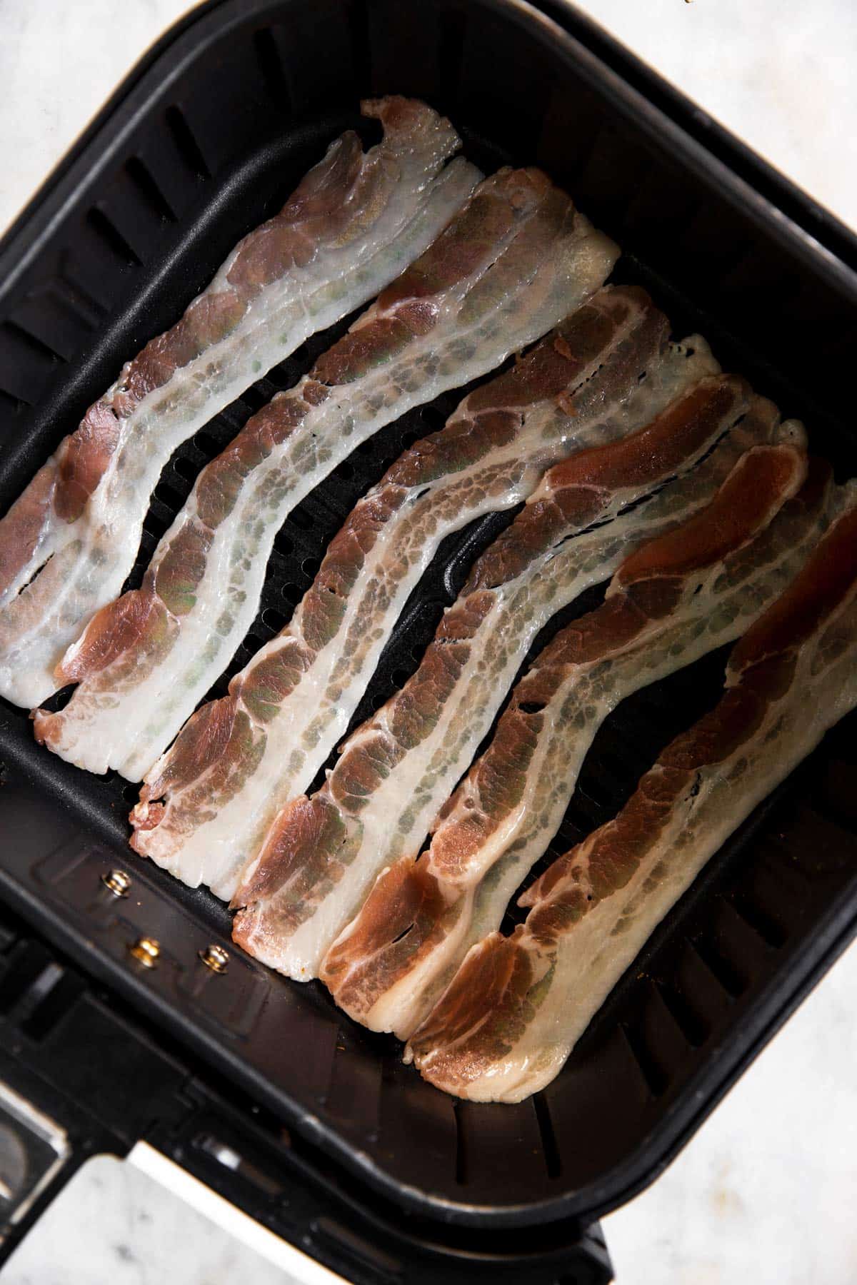 uncooked bacon in air fryer basket