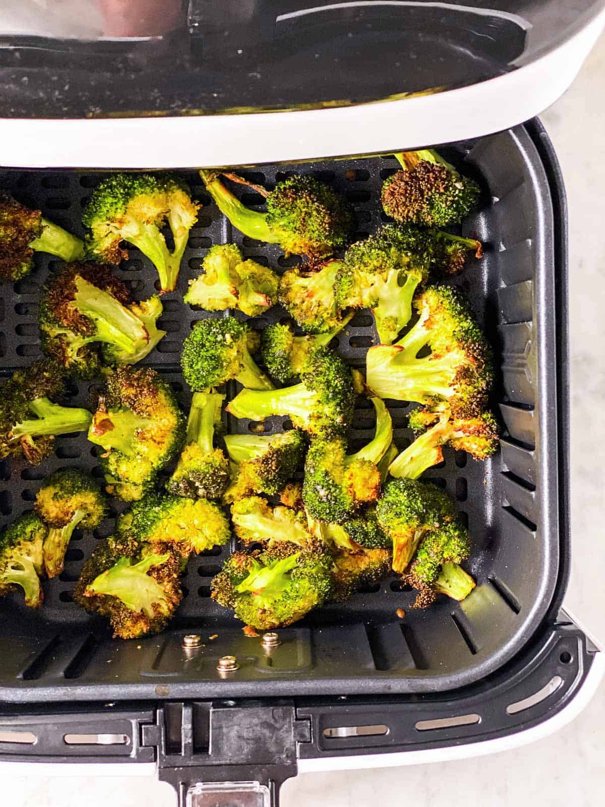 overhead view of roasted broccoli in air fryer basket